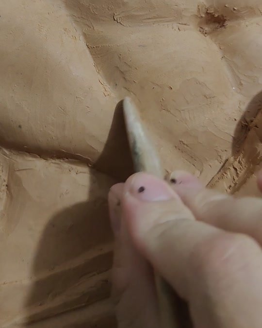Wuhua modeling a male-form relief in clay