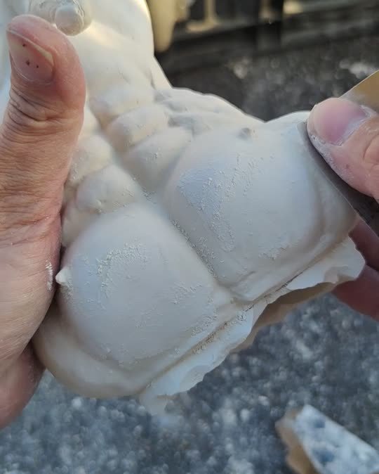 Hand refining the surface of a male torso sculpture